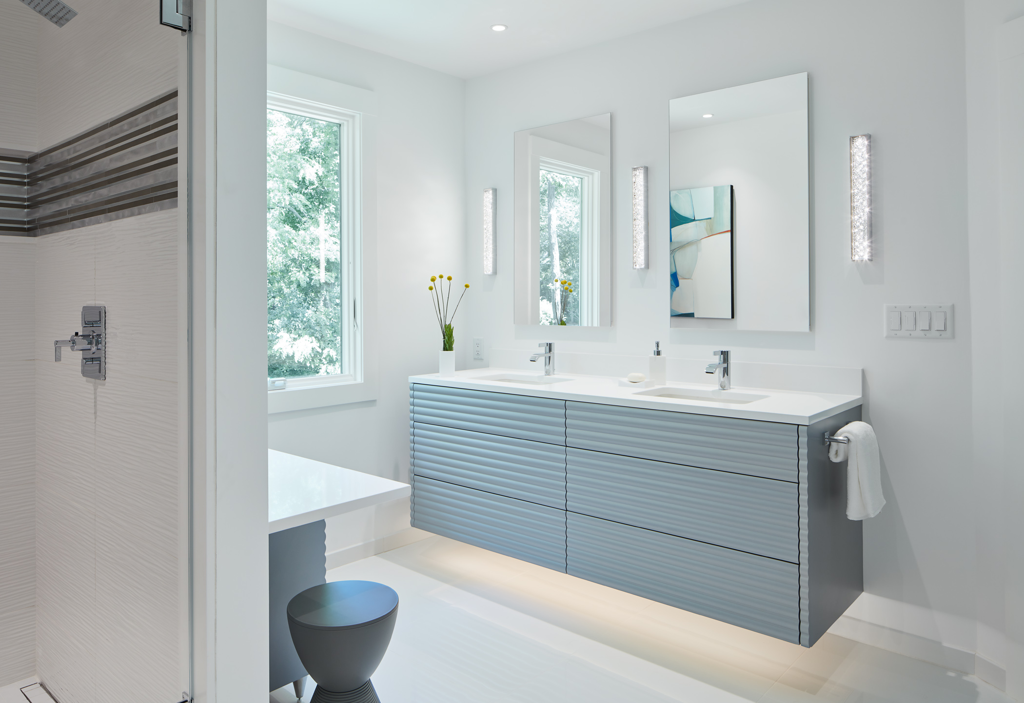 Modern bathroom with a double sink vanity, two mirrors, wall sconces, and minimalist decor in a bright, white space—an example of luxury interior design by a top interior designer in Massachusetts.