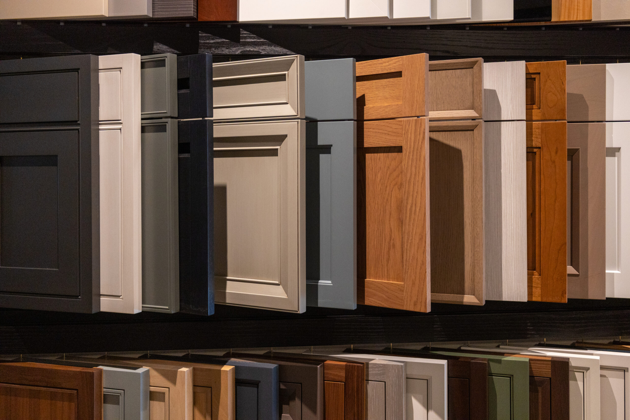 A display of various cabinet door fronts in different colors, materials, and styles, arranged on shelves in a showroom—a perfect inspiration for anyone seeking luxury interior design or an interior designer in Massachusetts.