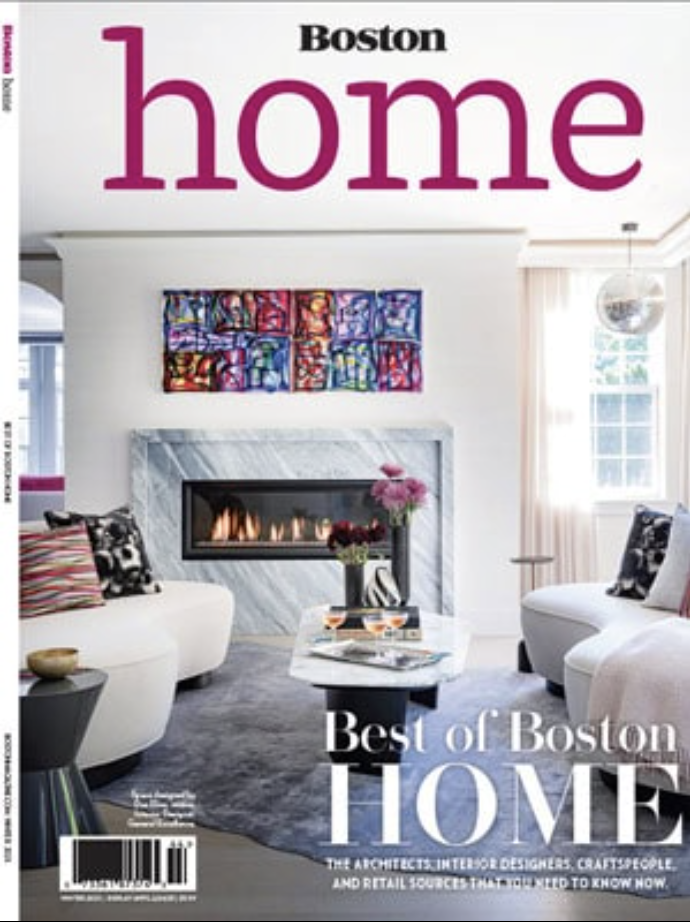 Cover of Boston Home magazine featuring a modern living room designed by an Interior Designer Massachusetts, with a marble fireplace, colorful art above it, white furniture, and decorative pillows—showcasing luxury interior design at its finest.