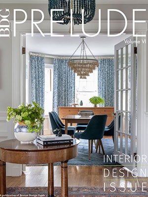 A round table with books and a vase sits in a hallway, leading to a dining room with a chandelier, blue chairs, and patterned curtains—an inspiring look at Luxury Interior Design. Text reads 