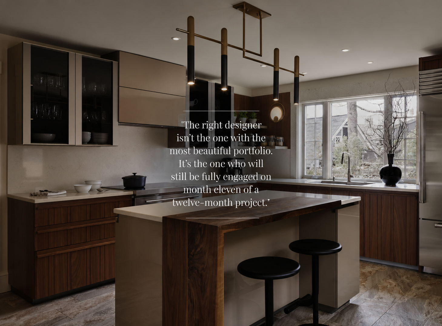 Modern kitchen with wood and beige cabinetry, a central island with two stools, pendant lighting, and large windows; motivational quote about design is overlaid on the image.