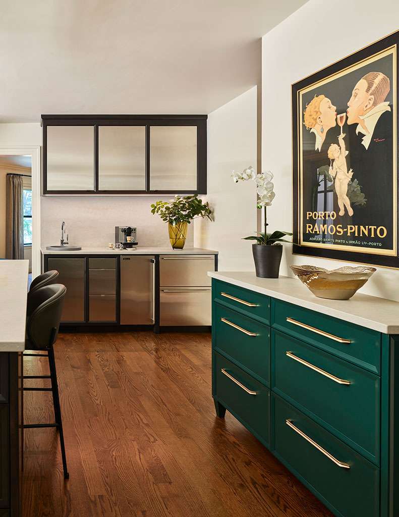 Modern kitchen with green lower cabinets, black and frosted uppers, wood floor, coffee maker, potted plant, and a vintage Porto Ramos-Pinto poster—perfect for those seeking luxury interior design by an Interior Designer Massachusetts.