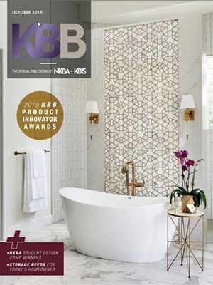 KBB magazine cover featuring a modern bathroom with a freestanding tub, geometric tile accent wall, gold fixtures, and a small table with a purple orchid—showcasing luxury interior design by an Interior Designer Massachusetts.