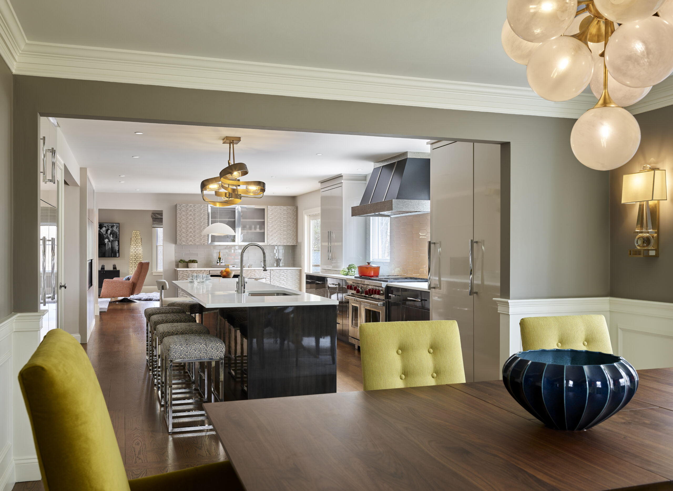 Modern open-concept kitchen and dining area with a wooden table, yellow chair, blue bowl centerpiece, island seating, and pendant lighting—perfectly styled for luxury interior design by a top Interior Designer Massachusetts.