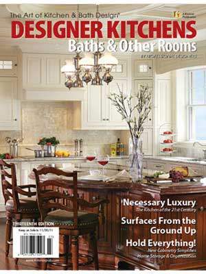 A modern kitchen with white cabinets, a large island with seating, pendant lighting, and decorative accents—showcasing Luxury Interior Design—featured on the cover of Designer Kitchens magazine.