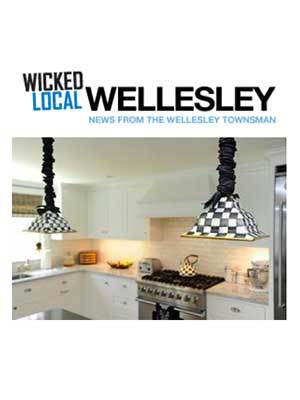 A modern white kitchen with checkered pendant lights, stainless steel stove, and cabinets, showcasing Luxury Interior Design and featured in Wicked Local Wellesley news.