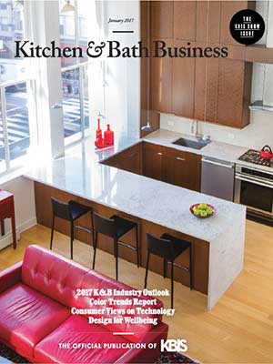 A modern kitchen with brown cabinets, a marble island with bar stools, and a red sofa, showcasing luxury interior design, featured on the cover of Kitchen & Bath Business magazine.